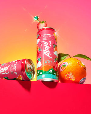 Two colorful energy drink cans with fruit graphics on a pink and red gradient background.