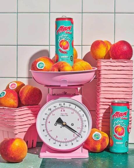Pink kitchen scale with peaches and Aland Energy Peach cans on a tiled background
